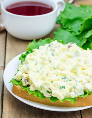 Sandwich with egg salad, bacon, green onion and lettuce