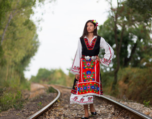 Girl with bulgarian costume on the railway line