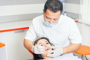 Dentist doctor treats teeth patient girl in dental office