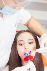 Obraz na płótnie Canvas Dentist doctor treats teeth patient girl in dental office