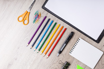 Paper, pencils, brush, green apple on wooden table