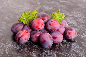 Fresh Dark Plums on black Table and mint