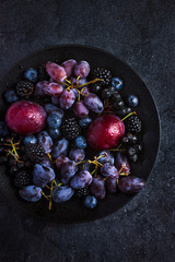 fresh dark fruits and berries on black background.