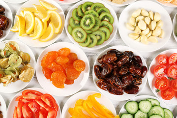 Different products on saucers on wooden table, top view