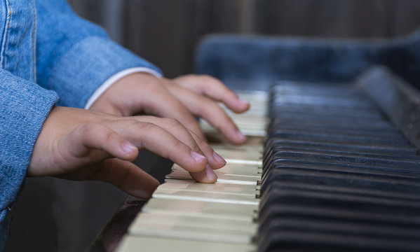 Child playing piano with selective focus and shallow depth of