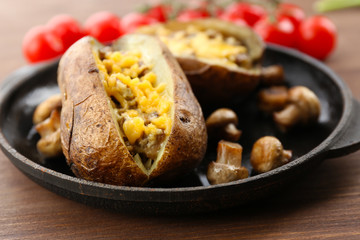 Baked potatoes with cheese and mushrooms on table close up