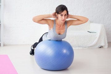 Fitness young woman doing abdominal crunches on fit ball.