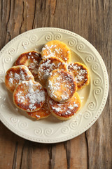 Fritters of cottage cheese in plate on wooden table, closeup