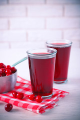 Two glasses with cherry juice on table, on light background