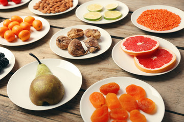 Different products on saucers on wooden table close up