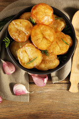 Delicious baked potato with rosemary in bowl on table close up