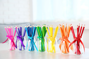 Bright pencils in glass jars on table