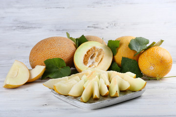 Ripe melons with green leaves on wooden background