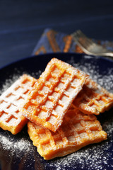 Sweet homemade waffles on plate, on dark wooden background
