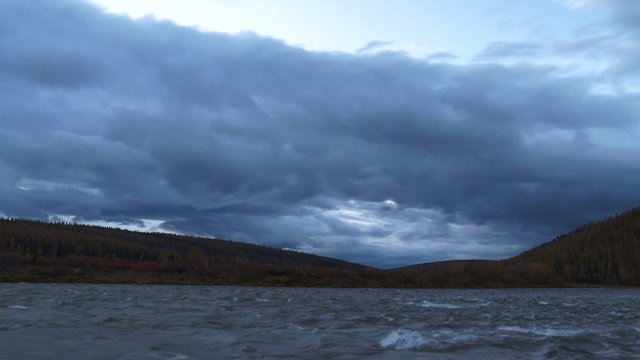 Nightfall on the River/ Dark clouds move quickly over the river at night. Twilight. Time lapse. River forest backdrop 