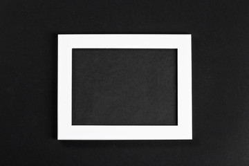 horizontal white photo frame with black field on black background isolated with real shadows
