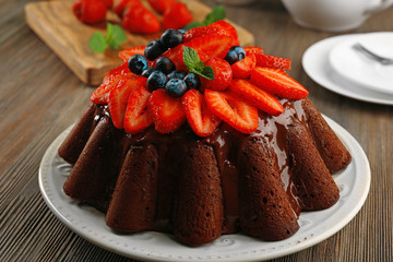 Delicious chocolate cake with berries in plate on table, closeup