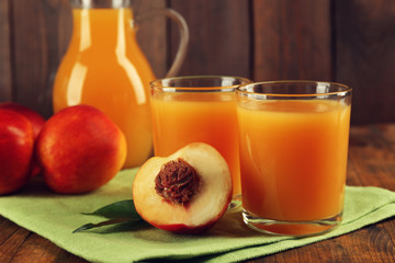 Peach juice and ripe peaches on wooden background