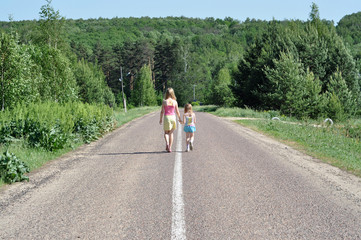 Obraz premium Two sisters walking on the road holding hands