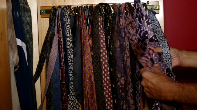 man choosing tie in the wardrobe