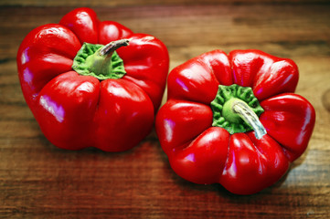 Two sweet red peppers on a wooden boards background
