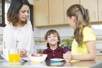 Obraz na płótnie Canvas Lovely Mother and her children having breakfast