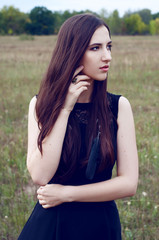 Woman with long dark hair and black feathers outdoors