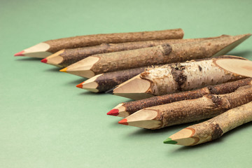 Colorful pencils made of wood, on green backdrop