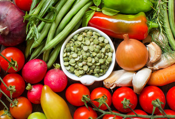 Green peas in a bowl between fresh vegetables