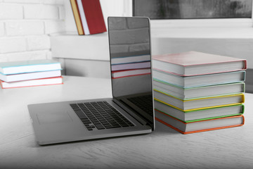 Stack of books with laptop on table close up