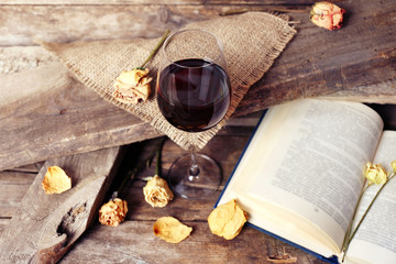 Beautiful composition with glass of wine with old book on table close up