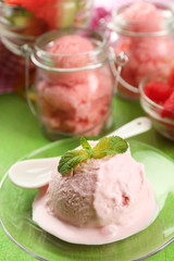 Watermelon ice cream in glass jar and on plate, on color wooden background