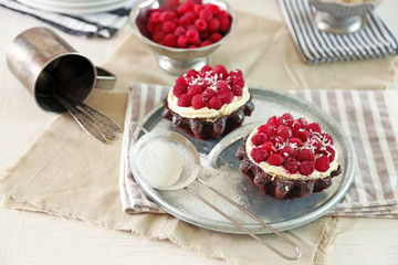 Sweet cakes with raspberries on light wooden background