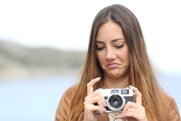 Upset woman looking her old slr photo camera