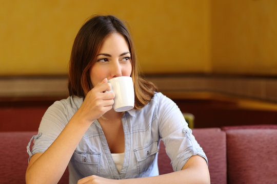 Relaxed woman thinking while is drinking a cup of coffee
