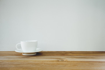 coffee cup on wooden table over white background. Vintage tone