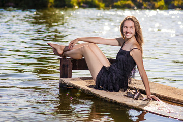 Sexy Sensual Caucasian Blond Woman Sitting on Pier Near Water an