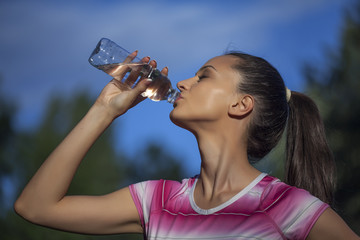 young sporty woman drinks water from a bottle