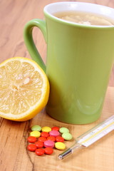 Pills, thermometer and hot tea with lemon for colds, treatment of flu and runny