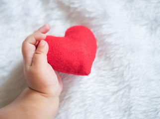 baby's hand with a red heart