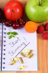 Fruits and tablets supplements with notebook, slimming and healthy food