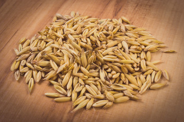 Vintage photo, Heap of organic oat grains on wooden table, healthy nutrition