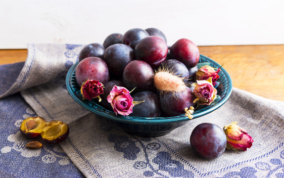 Purple plums in a green plate on a wooden table