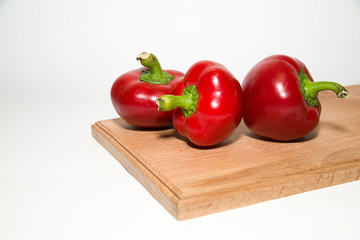 Three ripe red peppers on over white