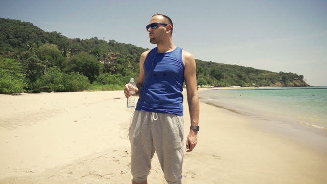 Male sportsman drinking water on beach
