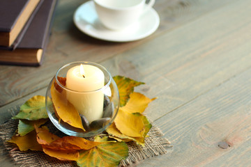 candle with leaves and books on wooden background