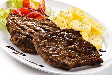 Grilled steaks, boiled potatoes and vegetable salad 