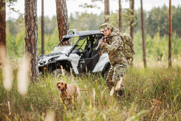 Hunter with Rifle and Four Wheeler Tire in forest