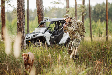 Hunter with Rifle and Four Wheeler Tire in forest