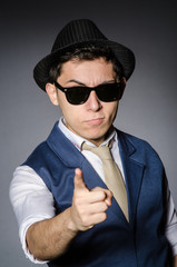 Young man in blue vest and hat against gray